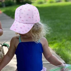 Pink kids baseball cap with rainbow pattern worn outdoors for sun protection