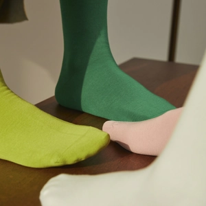 Bunte Strick-Crew-Socken in Grün und Gelb auf Holzoberfläche, hochwertige Baumwolltextur