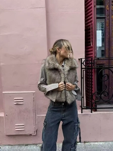 Outdoor street style view of a faux fur vest paired with a striped shirt and denim jeans