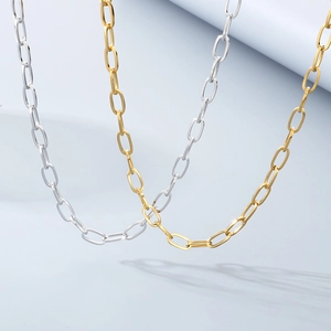 Detailed view of polished gold and silver paperclip chain necklaces on a blue step background