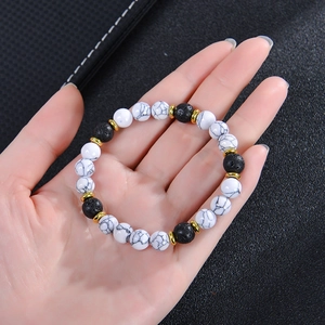 White turquoise and volcanic stone beaded bracelet with gold discs worn on wrist