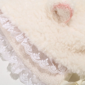 Detailed view of plush lamb velvet hat featuring white lace trim and satin bow ties
