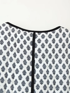 Close-up of quilted cotton fabric with dark blue leaf prints and black piped collar edge