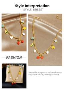 Detail view of gold beaded necklace with colorful enamel fruit pendants on silk fabric