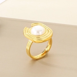 Macro shot of U-shaped gold textured ring featuring a central shell pearl inlay