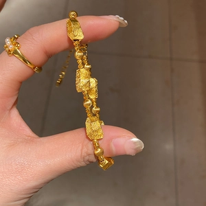Detail of gold bracelet with matte geometric links and pearl ring on hand