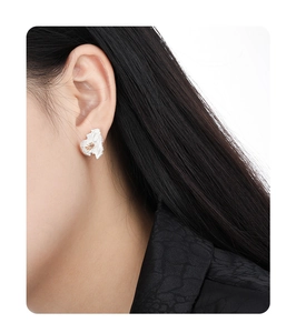 Close-up of asymmetrical S925 silver stud earring with crinkled texture and yellow gem