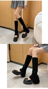 Close-up of black ribbed knit leg warmers paired with platform Mary Jane shoes