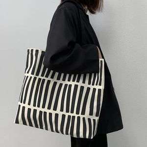 Close-up of minimalist black and white geometric striped canvas tote bag with zipper