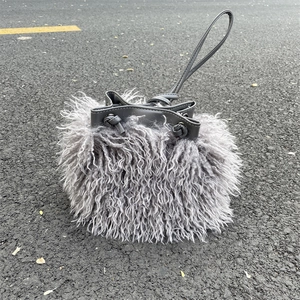 Close-up of grey faux sheepskin bucket bag with drawstring closure on ground