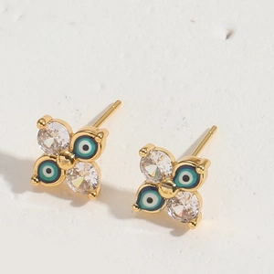 Macro shot of gold clover stud earrings with blue enamel evil eye and clear zircon stones