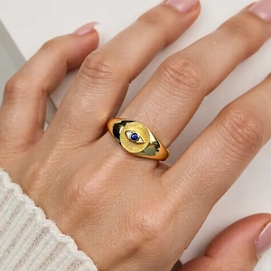 Detail of 18K gold-plated signet ring with engraved evil eye and blue zircon stone