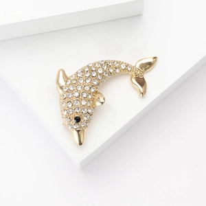 Fashionable gold dolphin brooch with sparkling crystals on a white pedestal for women