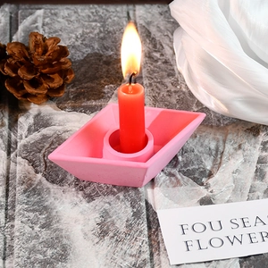 Detail of pink paper-boat shaped plaster candle holder with a lit red candle