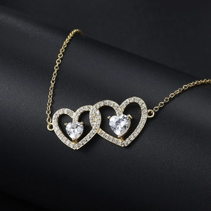 Macro view of interlocking gold double heart necklace with pavé set zircon stones