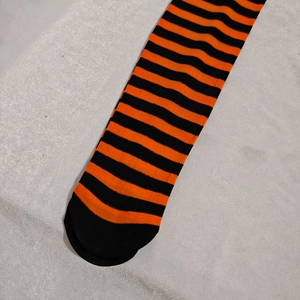 Detail of orange and black striped over-the-knee socks with reinforced black toe design
