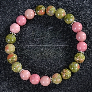 Macro shot of sunstone and rose quartz fertility bracelet on black leather backdrop