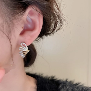 Close-up of golden butterfly stud earring with sparkling zircons worn by a model