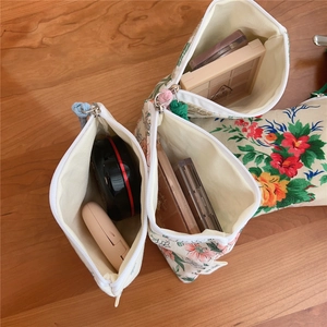 Floral canvas mini storage pouches with zippers and decorative pompoms on a wooden table