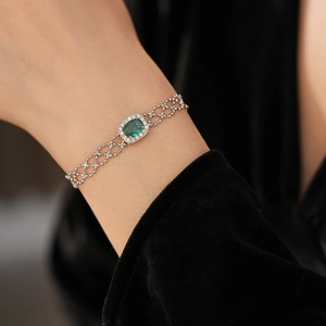 Detailed macro view of vintage silver bracelet with green emerald oval stone and pavé gems
