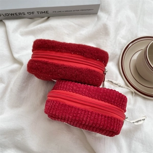 Detail of red plush and corduroy pouches with zipper and branded white ribbon strap
