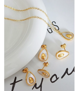 Macro shot of gold avocado-shaped jewelry set with mother-of-pearl inlay details