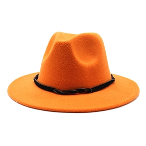 Detail of a bright orange wool fedora featuring a black woven band and flat wide brim