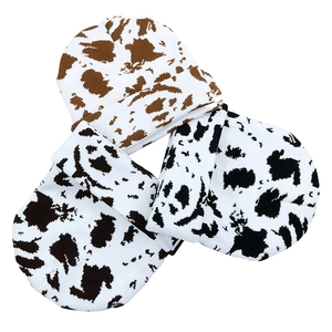 Detailed knit texture of cow pattern beanies in black, white, and brown colorways