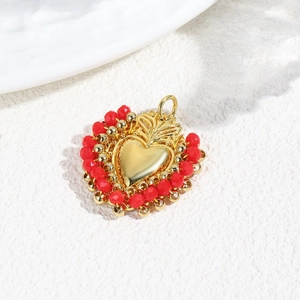Macro view of gold heart pendant with red beads and flame detail for DIY jewelry
