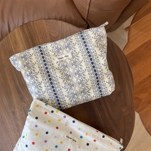 Floral and polka dot fabric makeup bags with zippers on a rustic wooden table