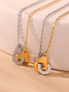Détails des pendentifs menottes bicolores or et argent sur une surface en pierre texturée