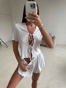 Dettaglio del pigiama all'uncinetto bianco con top a lacci e pantaloncini ondulati