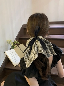 Détail d'un chouchou à carreaux noir et blanc avec ruban de satin sur les cheveux