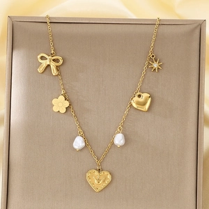Detailed shot of gold necklace with bow, pearl, and heart pendants on silk