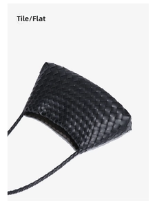 Flat lay view of a black hand-woven leather crossbody bag with a slim braided strap