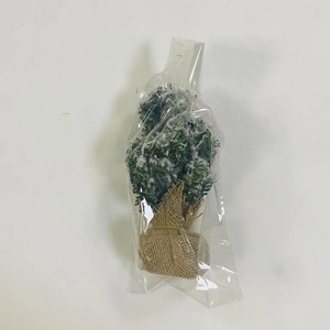 Close-up of a mini artificial Christmas tree with snow effect and burlap base in packaging