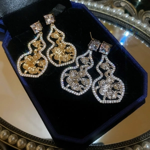 Detailed macro view of gold and silver hollow gourd earrings with rose floral relief