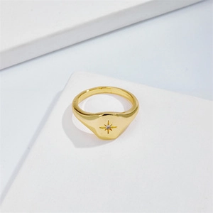 Detail view of gold dome ring with engraved North Star and zircon on white stand
