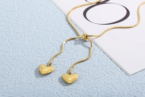 Detail of adjustable gold snake chain necklace featuring polished heart pendants