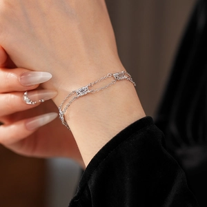 Detail view of double-layer silver bracelet featuring hollow floral and star pendants