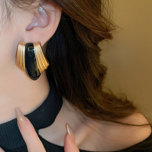 Close-up of vintage gold water drop earrings with black oil drip on model