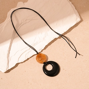 Detail of vintage resin round pendant with amber marble beads on a black cord necklace