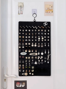 Detail of black felt jewelry organizer hanging on a door for earrings and sunglasses