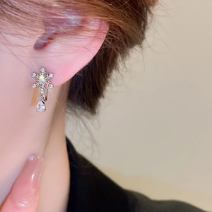Detail of silver snowflake earring with a teardrop zircon pendant on a model