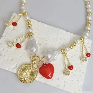 Detail of 18k gold plated necklace with red heart, cherry charms and pearls