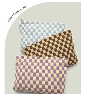 Close-up of checkered knit makeup bags in blue, brown and purple with metal zippers