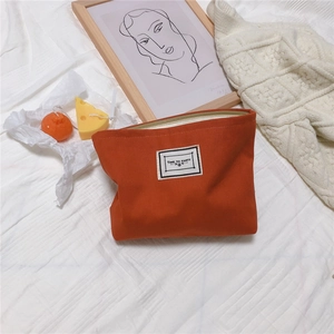 Detail of orange houndstooth canvas pouch with Time to Party tag on cozy bed