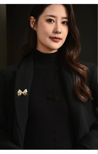 Golden bow-shaped brooch on a black blazer collar showcasing elegant fashion contrast