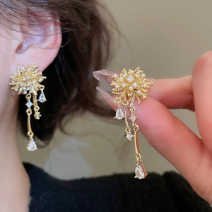 Detail of elegant gold-plated tassel earrings with fireworks pattern, pearls, and zircons