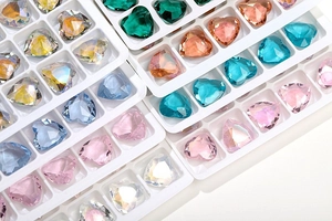 Macro detail of colorful 12mm heart shaped glass crystals in white organizer trays